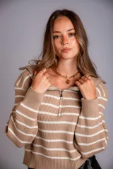 Sweater de punto color beige con rayas horizontales blancas, cuello polo con cierre de cremallera y mangas largas.