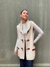 Chaleco largo color beige tejido en lana merino, con cuello alto y cierre frontal con botones de madera.