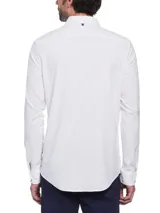 Camisa blanca de corte slim fit, cuello abotonado y mangas largas. Tiene un pequeño logo bordado en el pecho.