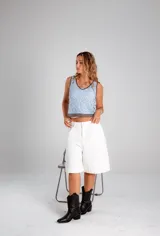 Blusa celeste de crochet con cuello redondo y ribete marrón.