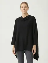 Poncho tejido de punto liso, color negro, con cuello tipo chimenea drapeado y mangas tres cuartos con puño acanalado. Presenta un corte asimétrico con caída.