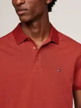 Chomba Tommy Hilfiger color ladrillo, de corte regular, con cuello clásico, cartera de tres botones y logo bordado en el pecho.