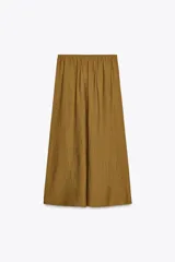 Falda midi color ocre de tejido arrugado con cintura elástica ajustable con cordones y bolsillos laterales ocultos en la costura.