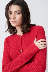 Chaqueta tejida roja con botones metálicos dorados y cuello redondo.
