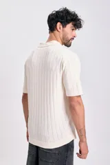 Sweater de tejido de punto color crudo, manga corta, con cuello polo y escote en V. Presenta un diseño acanalado vertical.