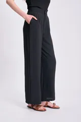 Pantalón negro de corte palazzo, con cintura alta y textura arrugada.