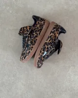 Zapatillas deportivas de cuero vacuno con estampado animal print de leopardo, detalles en cuero negro y suela marrón.