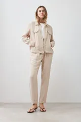 Chaqueta color beige melange de lino con pespuntes a contraste, cuello camisero, cierre frontal con botones, bolsillos de parche en el pecho y corte recto.