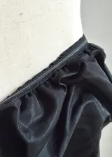 Top bandeau negro con textura fruncida y estampado abstracto plateado.