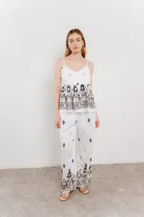 Pantalón blanco con estampado geométrico en azul y marrón, de calce relajado y caída fluida.