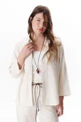 Camisa verde militar de manga larga con puños color crema, cuello clásico y cierre frontal con botones. Tiene un bolsillo en el pecho con bordado de una palmera color crema.