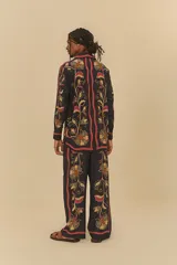 Pantalón negro con estampado floral en tonos naranja, amarillo y rojo. Corte holgado, cintura elástica de tiro medio y largo amplio.
