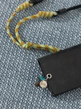 Tarjetero negro de cuero vacuno con broche imán y forrería de tejido jacquard. Incluye divisiones internas y correa combinada de cuero y cordón para colgar al hombro. Aplique Groovy en el frente.