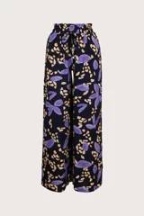 Pantalón de corte amplio con estampado de flores abstractas en tonos violeta y beige sobre fondo negro. Tiene aberturas laterales y jareta ajustable en la cintura.
