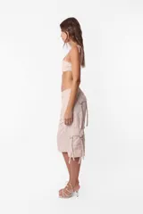 Conjunto de top y short color beige confeccionado en tela brillante. El top cuenta con arco metálico en el busto, tiras para atar en el hombro y ganchos lenceros en la espalda. El short es de tiro alto con cintura elastizada y bolsillos laterales.