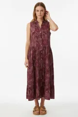 Vestido largo sin mangas de algodón con estampado de hojas y flores en tonos borgoña, cuello camisero y botones frontales. Corte holgado con falda escalonada.