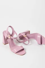Sandalias de tacón alto color lila, con tira delantera y tobillera con hebilla dorada.