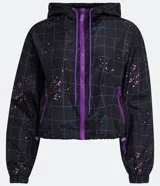 Campera cropped con capucha, de poliéster color negro con estampado de cuadros y salpicaduras de colores. Tiene cordón de ajuste en la capucha, elástico en puños y ruedo, bolsillos con cremallera y cierre frontal con cremallera.