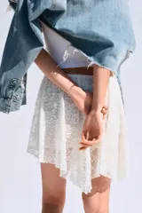 Falda corta de encaje color crema con forro interior. Presenta cintura elástica y bajo asimétrico con terminación en picos.