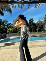 Top corto plateado, estilo bandeau, con tirantes finos y flecos largos en el bajo.