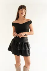 Minifalda negra de seda fría tornasolada, con faja en la cintura y volados.