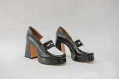 Mocasines negros de cuero con plataforma y tacón cuadrado. Presentan detalle de antifaz blanco en la capellada.