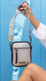 Phonebag color mostaza con bolsillo frontal con cierre, espacio para celular y billetera con repartición. Tiene una correa gruesa de galón regulable y desmontable. Detalles en marrón y beige.