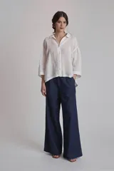 Camisa blanca de lino con cuello clásico, cierre frontal con botones y mangas 3/4 abullonadas.