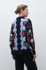 Camisa de manga larga, color azul marino, con estampado floral en tonos rojo, blanco y celeste. Presenta un diseño frontal con paneles ondulados en color celeste claro.