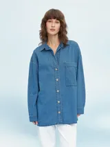 Camisa de denim celeste, de corte oversize, manga larga y cierre frontal con botones.