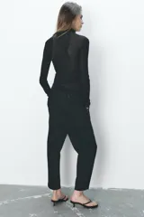 Pantalón de jean negro con efecto lavado, tiro alto, corte carrot fit, cintura elástica en la parte trasera, bolsillos delanteros y traseros, cierre frontal con cremallera y botón metálico.