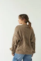 Sweater marrón de punto trenzado con cuello redondo y mangas largas abullonadas.