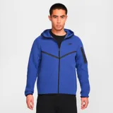 Campera deportiva Nike Tech Fleece color azul con cierre frontal, capucha y detalles en negro. Incluye logo de Nike bordado en el pecho y bolsillo con cierre en la manga izquierda.
