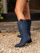 Bota texana de caña alta color beige, confeccionada en cuero vacuno con cierre interno YKK. Presenta bordados decorativos en la caña y taco de madera con folia de cuero.