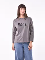 Remera gris con cuello redondo y mangas largas. Estampado frontal con la palabra "ROCK" en letras negras con efecto desgastado.