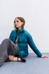 Campera puffer metalizada color azul petróleo, con cuello alto, cierre frontal y bolsillos con cierre. Tiene ajuste interno en el ruedo.