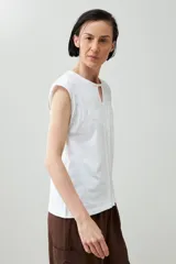 Remera de manga corta color verde agua con bordado floral blanco en la zona del pecho y cuello con abertura en forma de lágrima.