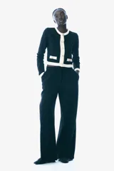 Saco corto negro de punto fino suave con cuello redondo, botones metálicos dorados y bolsillos insertados decorativos con botón adelante.