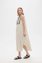 Vestido largo color crema con rayas verticales finas en negro, escote en V con ribete negro y corte holgado.