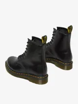 Bota de cuero negro Dr. Martens modelo 1460 W, de caña media con 8 ojales, costuras amarillas en la suela y tira con logo en el talón.