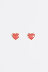 Caravanas de tipo botón con forma de corazón en color rosado y borde dorado. Presentan el nombre de la marca grabado en el centro. Están confeccionadas en latón con acabado esmaltado.