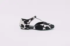 Zapato flat de cuero con estampado de vaca en blanco y negro, con tira delantera y hebilla lateral.