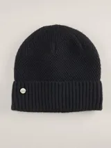 Gorro de lana color azul marino con textura tipo waffle y detalle de etiqueta metálica con logo de la marca en el lateral. Tiene borde acanalado.