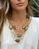 Collar en tonos dorados y crudos, compuesto por eslabones y piezas decorativas.