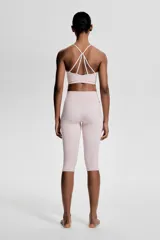 Top deportivo color rosa claro, de sujeción suave, confeccionado en tejido funcional con tecnología SoftMove™ y DryMove™. Tiene breteles finos cruzados en la espalda y copas forradas con relleno extraíble.