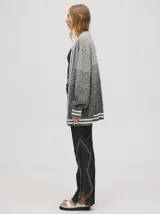 Cardigan tejido de punto con patrón de rombos en degradé de grises y blanco. Tiene corte oversize, mangas largas y cierre frontal con botones.