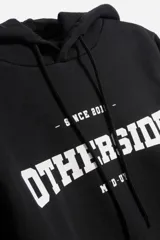Buzo hoodie gris con estampado azul con la palabra "OTHERSIDE" y las siglas "OTH" en estilo universitario.