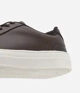 Championes casuales de cuero color marrón oscuro con cordones y suela blanca.