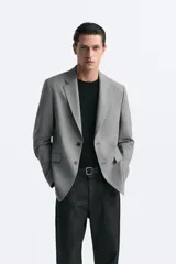Blazer straight fit color gris claro confeccionado en tejido con viscosa. Tiene cuello con solapas de muesca, manga larga acabada en puño con botón, bolsillo de vivo en pecho, bolsillos de plastrón en cadera y bajo con aberturas en espalda. Cierre frontal de botonadura.