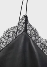 Vestido corto negro de estilo lencero con tirantes finos y escote en V adornado con encaje negro.